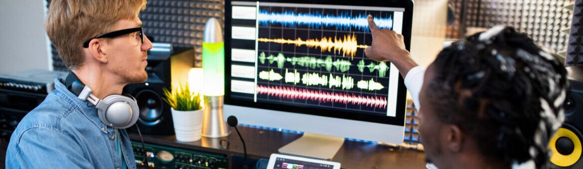 Contemporary musicians on work placement pointing at sound waveform on computer screen