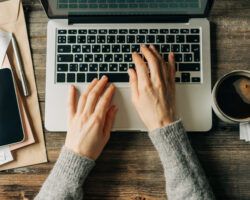 Top view of female hands typing on a laptop keyboard.