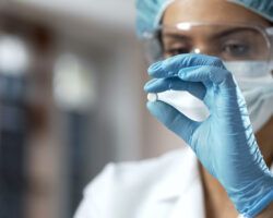 Female chemist looking at white pill, new medication testing in laboratory