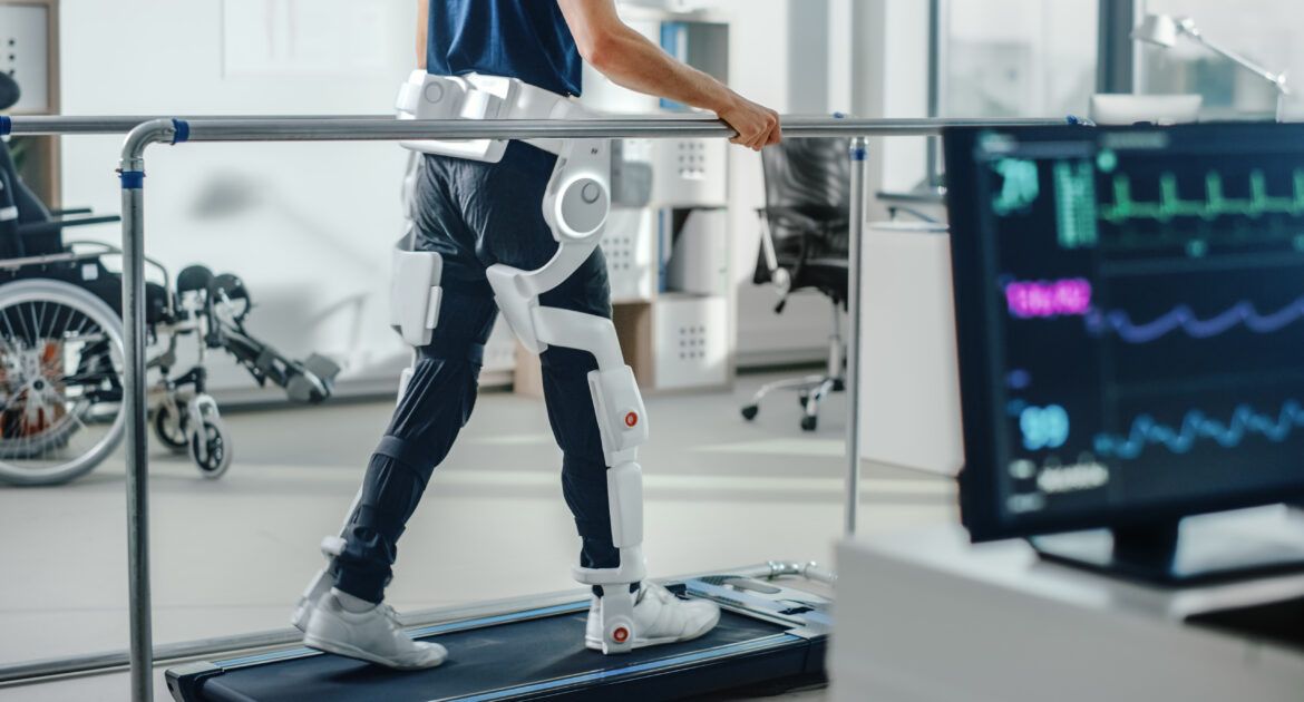 Modern Hospital Physical Therapy: Patient with Injury Walks on Treadmill Wearing Advanced Robotic Exoskeleton Legs. Physiotherapy Rehabilitation Technology to Make Disabled Person Walk. Focus on Legs