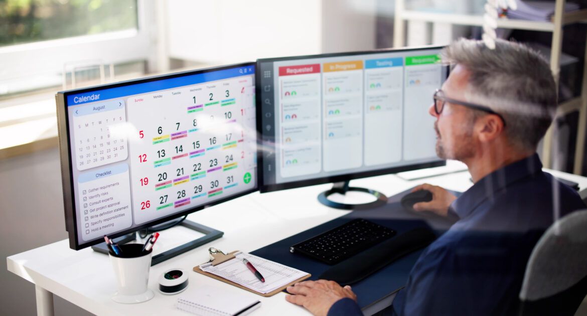 man sitting at computer planning work in the calendar