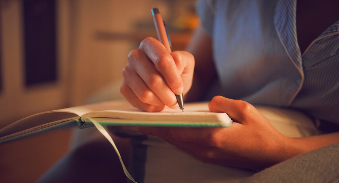 Creative writing at home by female hands enjoying a calm, peaceful day off indoors. Woman making notes in a journal, expressing her feelings and thoughts while making a note of a personal experience