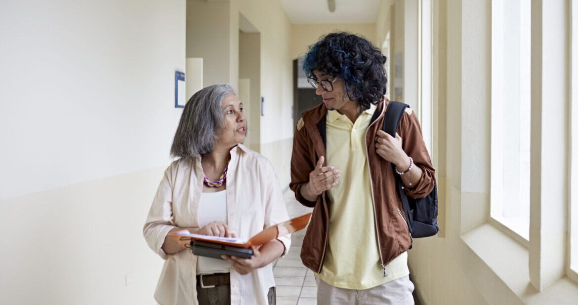 University tutor and student walking down university corridor