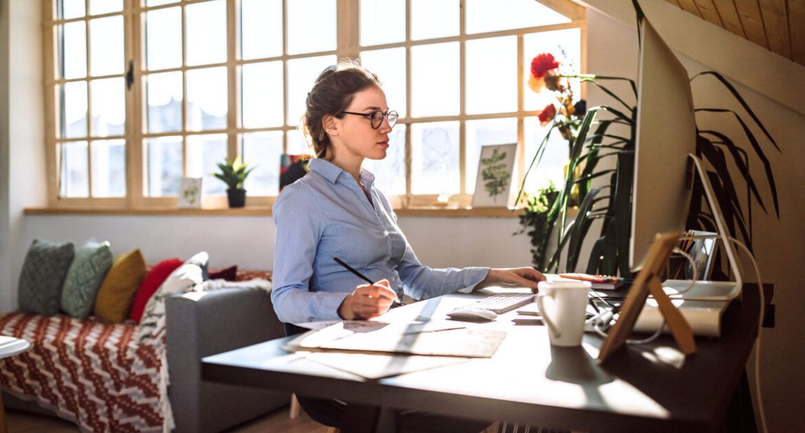 young woman sitting at her desk in front of pc at home